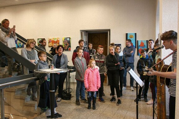 Kleine und große Gäste lauschen der Musik im Treppenhaus des Rathauses Öhringen